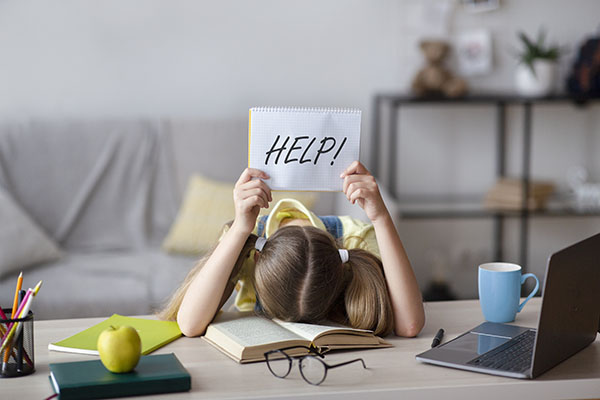 Child with dyslexia is having trouble reading and is holding up a help sign.